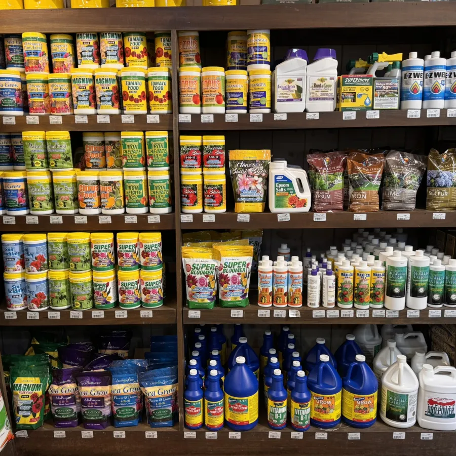 Shelves stocked with various gardening fertilizers, plant nutrients, and soil conditioners in bright packaging.