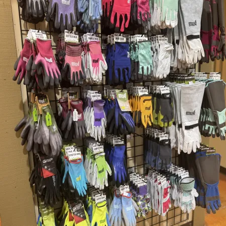 Colorful assortment of gardening gloves hanging on a display rack with various styles and sizes.
