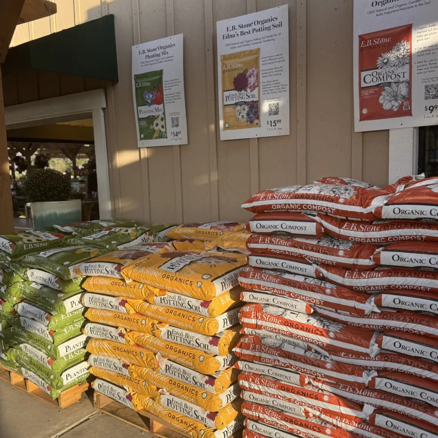 Stacks of E.B. Stone Organics planting mix, potting soil, and organic compost bags displayed outside a garden store.