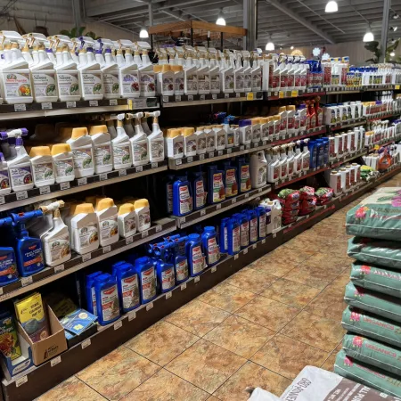 Aisle in a garden store with shelves stocked with various plant care products and fertilizer bags stacked nearby.