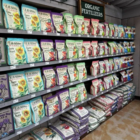 Shelves stocked with various organic fertilizers in colorful bags under an Organic Fertilizers sign in a store.