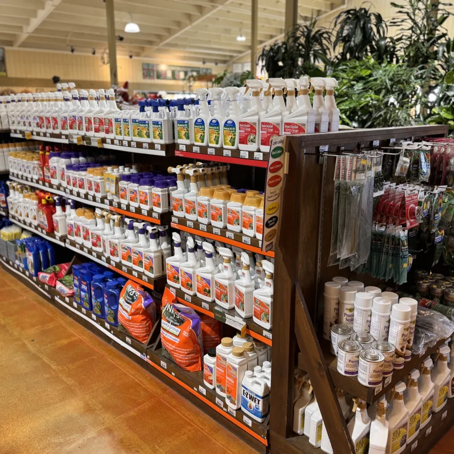 Shelves stocked with various gardening and plant care products in a well-lit garden center aisle