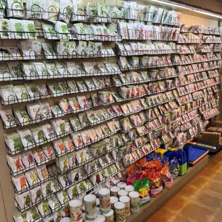 Wall-mounted racks filled with various seed packets and gardening supplies in a store aisle with brown flooring.