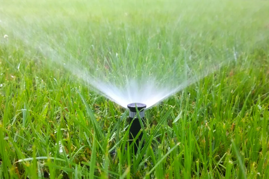 automatic sprinkler spraying water on grass